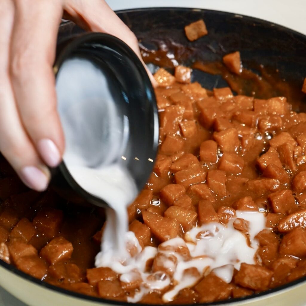 Pouring the cornflour (cornstarch) mixture into the cooked cinnamon-spiced pears to thicken the filling for Pear Cloud Cubes.