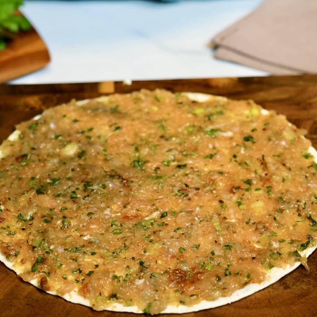 Chicken mixture evenly spread over a flour tortilla, ready to be topped with another tortilla and cut into twists.