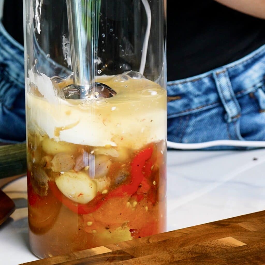 Blending roasted vegetables with cream cheese and vegetable stock.