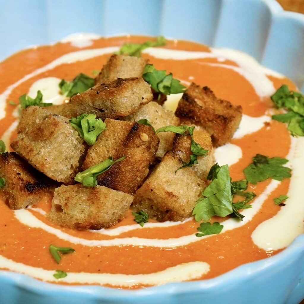 Close-up of creamy roasted red pepper and sweet potato soup in a bowl.