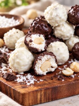 Coconut Cottage Cheese Bites on a wooden board, with a few cut in half to show the filling.