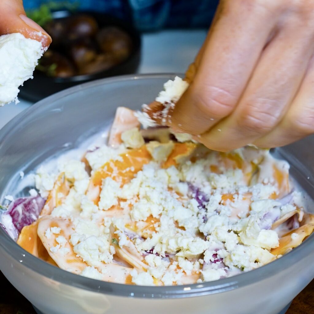 Crumbling feta over the bottom layer of butternut squash and purple sweet potato.