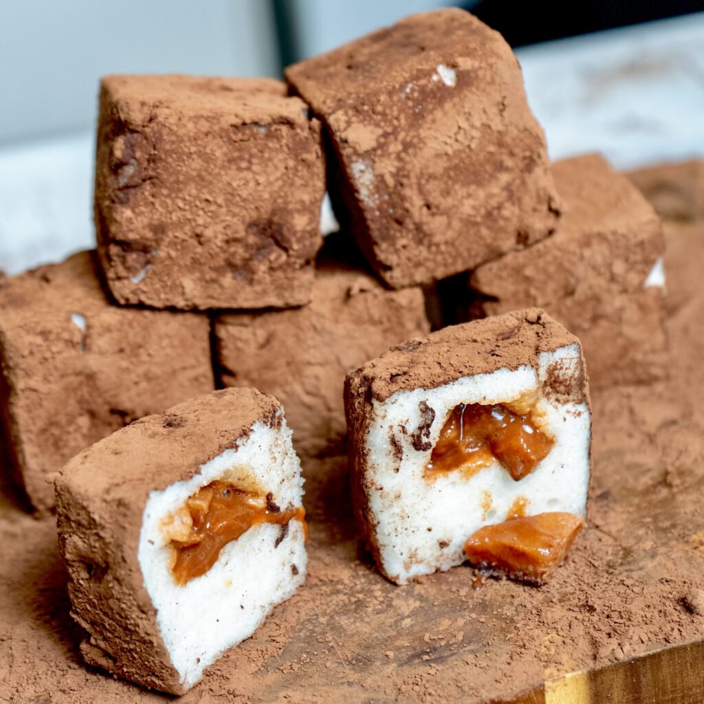 Cocoa-dusted Pear Cloud Cubes with Cinnamon Filling served on a wooden board, showcasing the fluffy no-bake dessert.