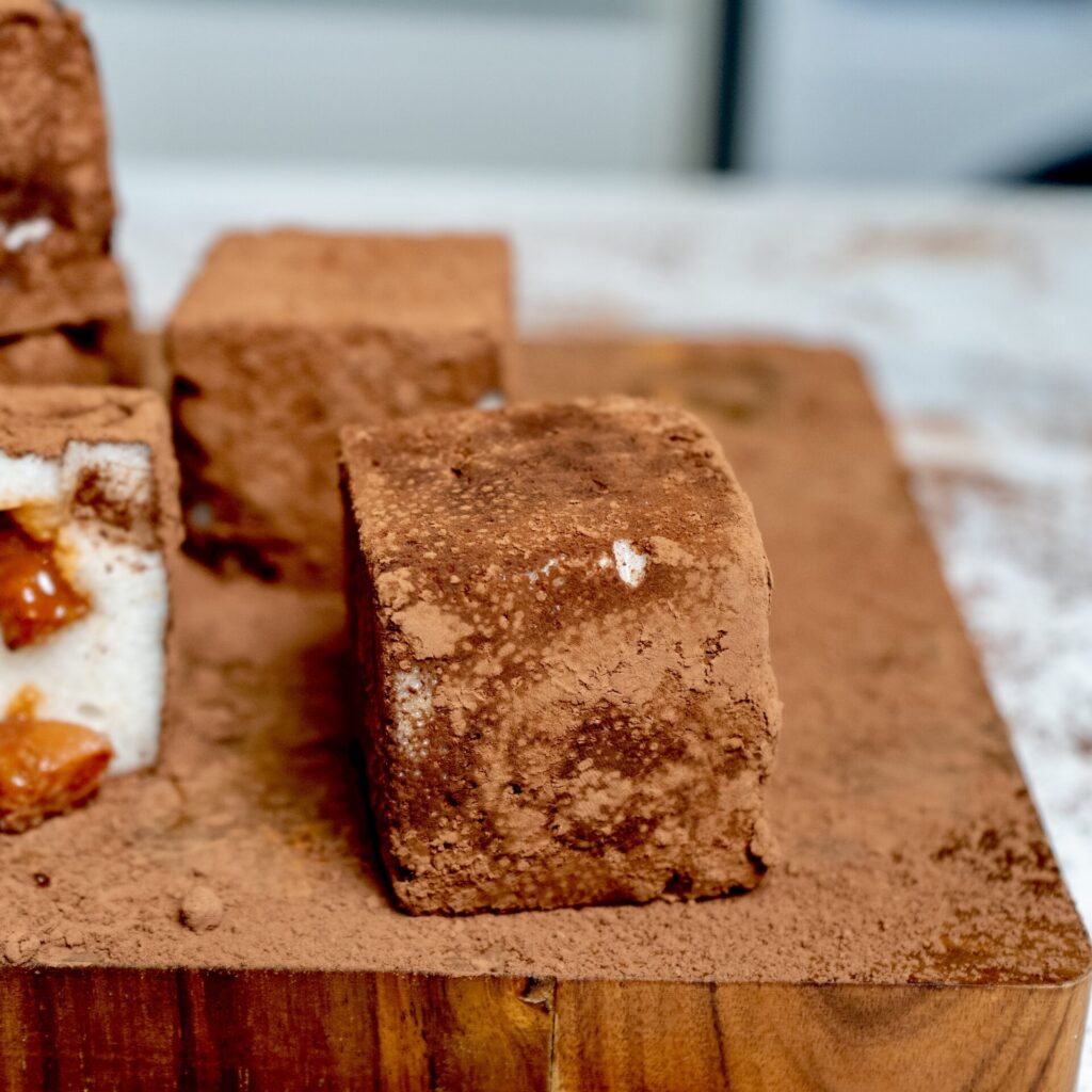 One cocoa-dusted Pear Cloud Cube with Cinnamon Filling served on a wooden board.